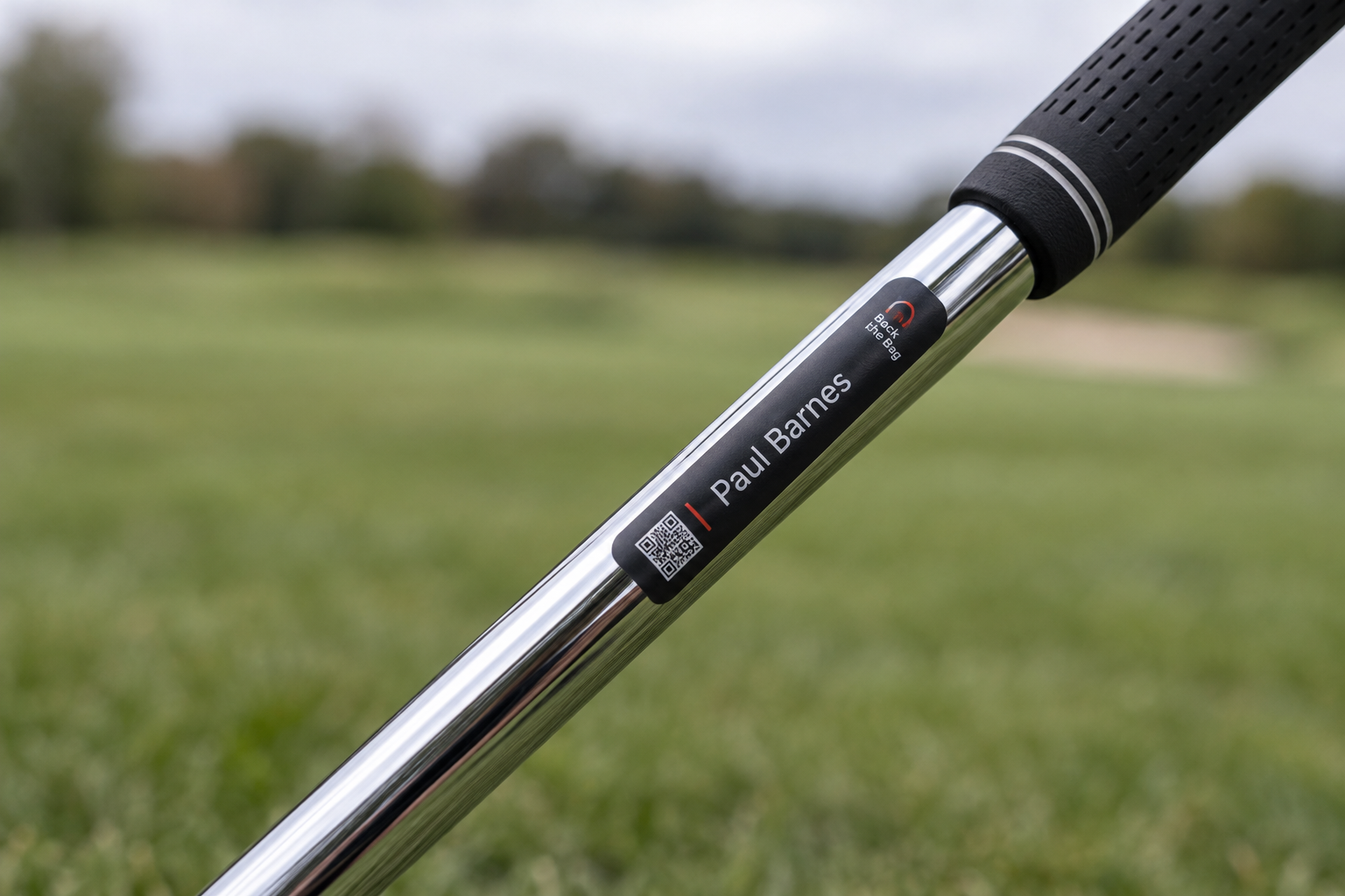 Close-up from the underside of an iron shaft, showing a Paul Barnes recovery label running lengthways below the grip
